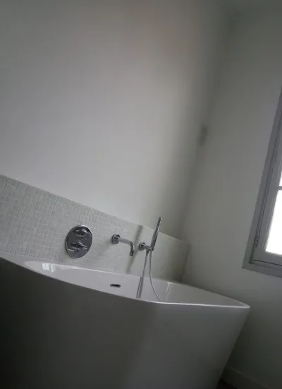 Salle de bains moderne repeinte en blanc, baignoire îlot et crédence en mosaïque