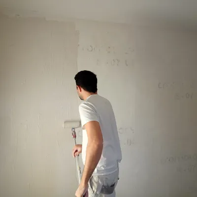 Artisan peintre appliquant une sous-couche crème au rouleau sur un mur intérieur