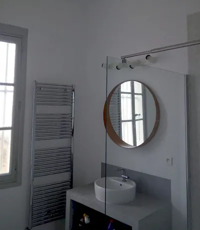 Salle de bain repeinte en blanc, miroir rond et sèche-serviettes, résultat fini