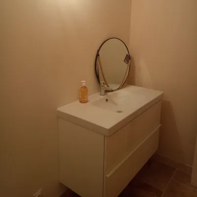 Salle de bain avec murs beige clair fraîchement peints, vasque et miroir ovale