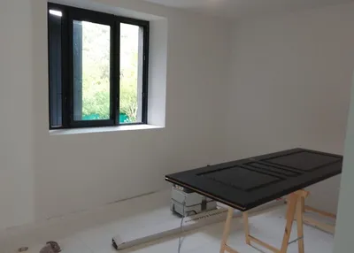 Porte laquée noir mat posée sur tréteaux dans une pièce vide en rénovation