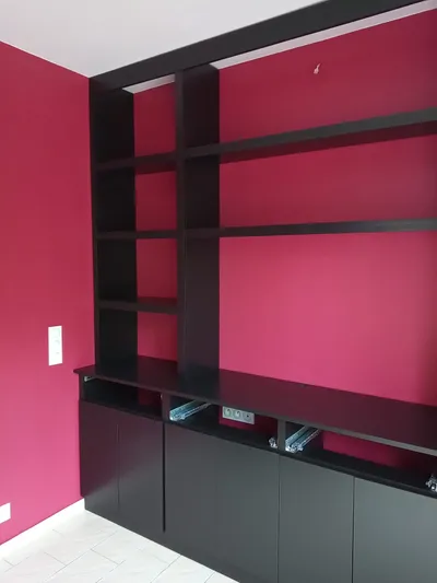 Salon aux murs rose vif fraîchement peints avec bibliothèque noire intégrée
