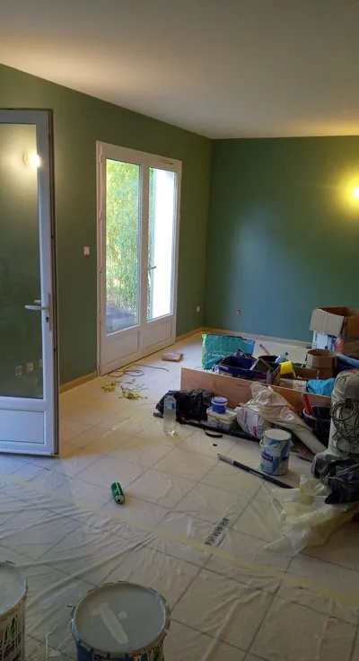 Pièce en cours de peinture, murs vert sauge, sol carrelé protégé par des bâches