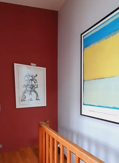 Palier peint en rouge et blanc avec cadres décoratifs et rambarde en bois