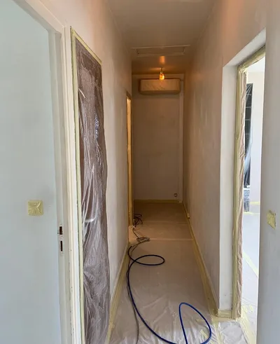 Couloir protégé de bâches avant peinture, murs enduits et portes marouflées