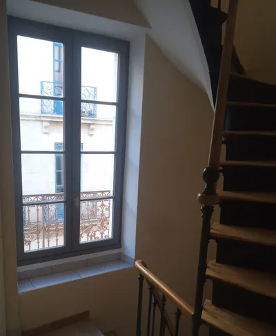 Escalier en bois et fenêtre repeinte en gris anthracite, vue sur balcon en fer forgé