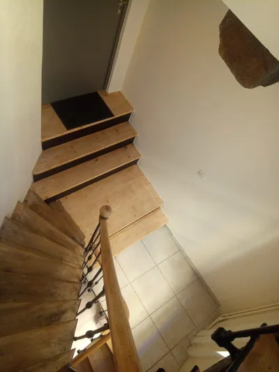 Escalier en bois vu d'en haut, marches rénovées et sol carrelé en contrebas