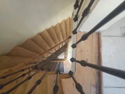 Vue plongeante sur un escalier en bois avec rampe en fer forgé travaillée