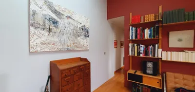 Couloir décoré, mur blanc avec tableau et pan de mur rouge doté d'une bibliothèque