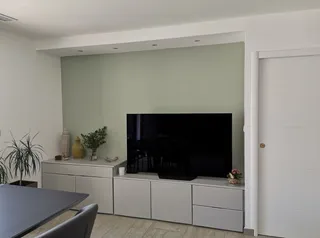 Salon avec mur d'accent vert sauge peint derrière un meuble TV