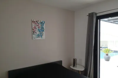 Chambre avec mur beige rosé clair, porte vitrée donnant sur la piscine
