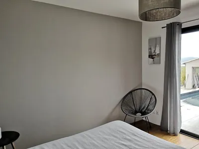 Chambre avec mur d'accent taupe, angle de pièce et vue sur la piscine