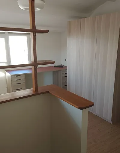 Mezzanine avec plafond incliné peint en blanc, poutres apparentes et armoire