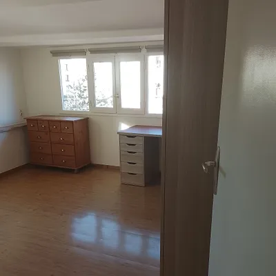 Chambre aux murs blancs fraîchement repeints, parquet bois et fenêtre à volets