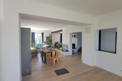 Séjour ouvert repeint en blanc, poutre apparente et sol clair, vue d'ensemble