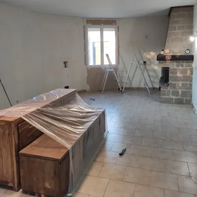 Séjour en cours de peinture, meubles protégés sous bâche et échelles en place