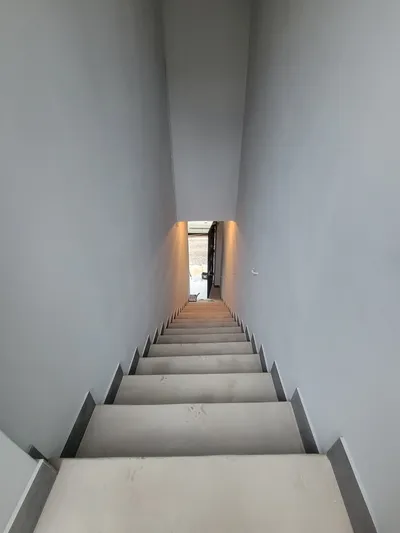 Cage d'escalier intérieure aux murs gris fraîchement repeints, vue plongeante vers le bas